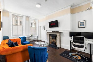 A modern living room with a fireplace, a mounted television, and a seating area with a sofa and chairs. - Oriental Nine | By My Getaways (Brighton)