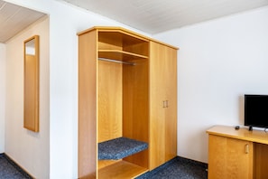 A room with a wooden wardrobe, a small desk with a television, and a mirror on the wall. - Room 'Einzelzimmer' with Wi-Fi (Friedewald)