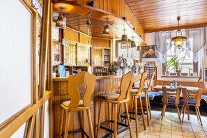 A bar area with wooden bar stools, a wooden counter, and hanging light fixtures. - Room 'Einzelzimmer' with Wi-Fi (Friedewald)