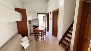 A compact living space with a kitchenette, a dining area, and a staircase. - Charming Semi-detached Villa Near the Beach (Valledoria)