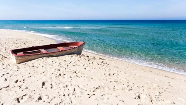 A boat on a sandy beach with clear blue water. - Charming Semi-detached Villa Near the Beach (Valledoria)