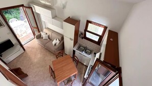 A compact living space with a kitchenette, a dining area, a sofa, and a window. - Charming Semi-detached Villa Near the Beach (Valledoria)