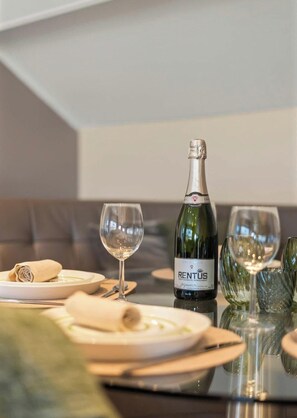 Une table à manger avec une bouteille de vin RENTUS, deux verres à vin et une serviette pliée.