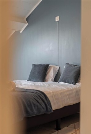 A bedroom with a bed, pillows, and a wall-mounted light fixture. - Esplanade Promenade - stay within walking distance of the beach (De Panne)