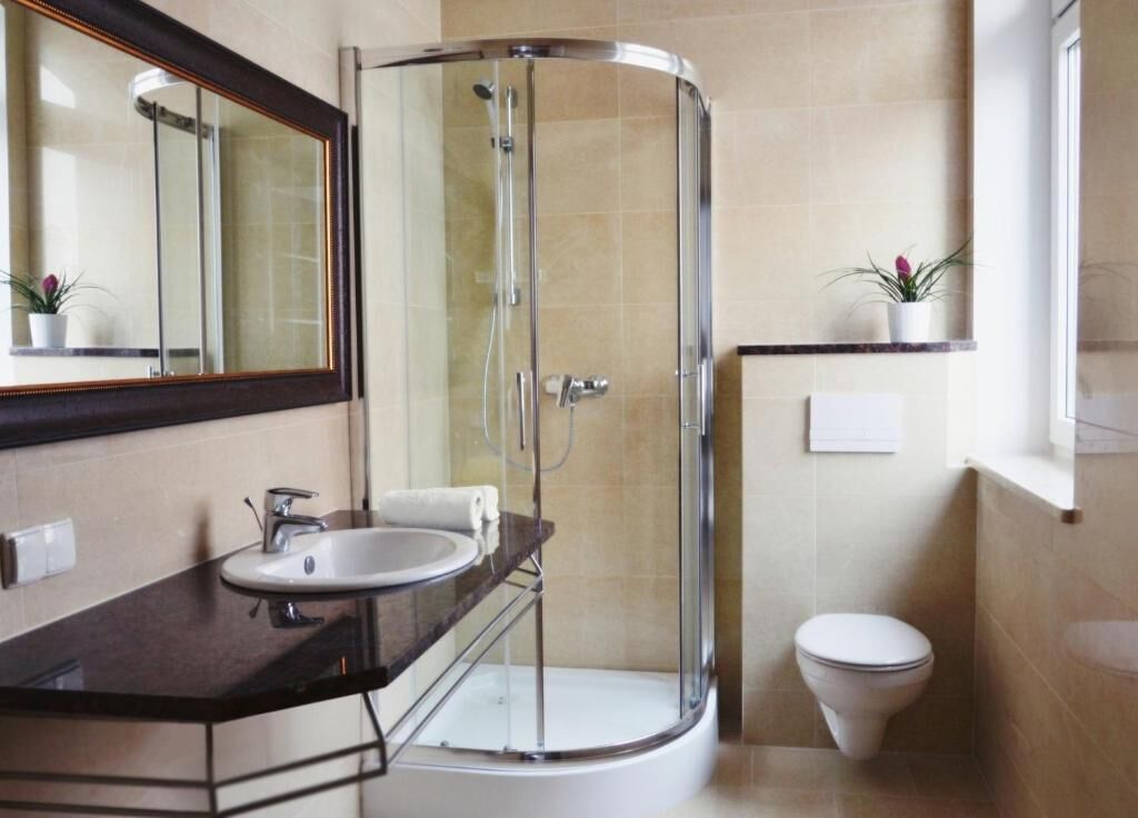 A modern bathroom with a glass-enclosed shower, a sink with a mirror, and a toilet.