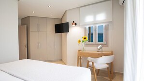 Une chambre à coucher avec un lit, un bureau et une chaise, une télévision et une fenêtre donnant sur un beau paysage.