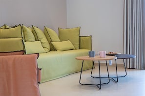 A living room with a sofa, a round coffee table, and a chair. - Enalion Apartments (Lefkada)
