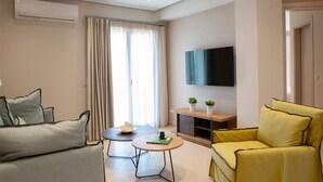 Un salon moderne avec un canapé, un fauteuil jaune, une table basse, un téléviseur à écran plat et une fenêtre avec des rideaux.