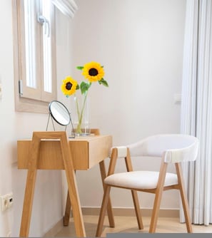 A room with a wooden desk, a chair, a mirror, and a vase with sunflowers. - Enalion Apartments (Lefkada)