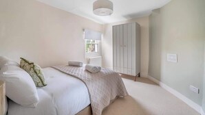 Une chambre à coucher avec un lit, une armoire, une fenêtre et un luminaire au plafond.