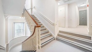 Un escalier aux murs blancs et à la rampe en bois menant à un palier.