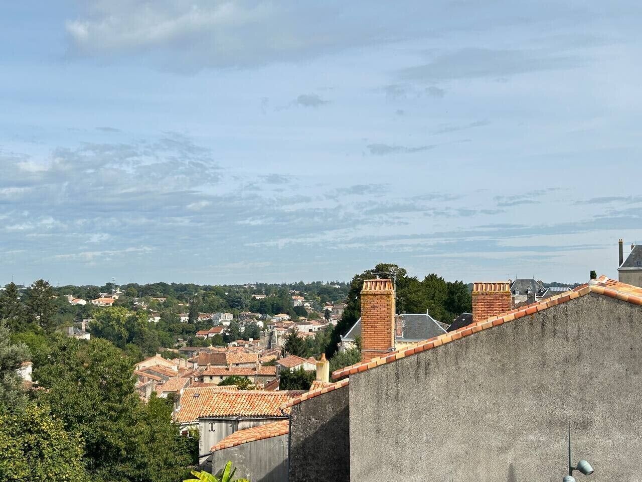 A view of a town with buildings, a prominent chimney, and a clear sky.
