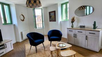 A modern living room with two blue armchairs, a small wooden table, a mirror, and a cabinet.