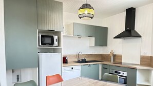 Una cucina compatta con forno a microonde, lavello e fornello, e un tavolo da pranzo con sedie.
