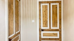 Una porta in legno con stipite bianco, un interruttore della luce e un campanello.