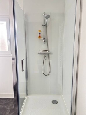 A glass-enclosed shower with a handheld showerhead and a wall-mounted faucet. - 2 bedroom apartment - Downtown Parthenay (Parthenay)