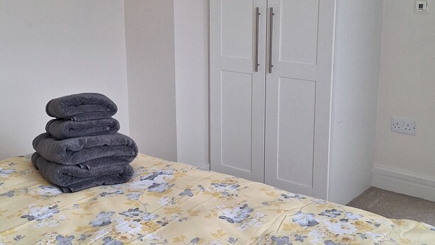 A bedroom with a bed, a wardrobe, and a small shelf with a reed diffuser. - Centrally Located 2bed Duplex (Westport)