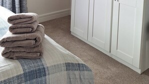 A bedroom with a bed, a white wardrobe, a hanging light, and a window with curtains. - Centrally Located 2bed Duplex (Westport)