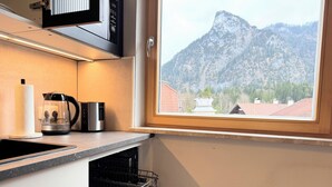 A kitchen with a coffee maker, a kettle, and a dish rack. - Chic Alpine Oasis Oberammergau with Mountain View (Oberammergau)