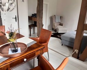 Ein modernes Wohnzimmer mit einem Holzes Esstisch, Ledersesseln, einer Couch und einer dekorativen Vase.