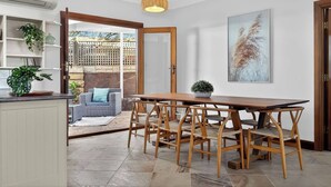 Een keuken met een eettafel, stoelen, een hanglamp en uitzicht naar buiten.