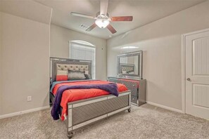 A bedroom with a bed, a ceiling fan, a window with blinds, a dresser, and a door. - Spacious 6-bedroom house with lake in beautiful Missouri City (Missouri City)