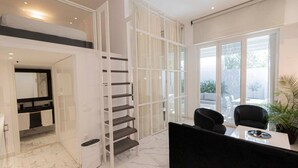 A modern interior with a staircase, a dining area, and a view through large windows. - 4 Elemental Living Suites - Wind (Nea Moudania)
