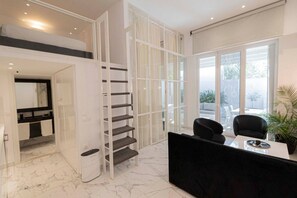 A modern interior with a staircase, a dining area, and a view through large windows. - 4 Elemental Living Suites - Wind (Nea Moudania)