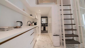 A modern kitchen with a coffee maker, a kettle, and a trash bin. - 4 Elemental Living Suites - Wind (Nea Moudania)