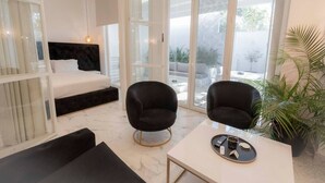 A modern room with a bed, two black chairs, a table with a tray of items, and large windows. - 4 Elemental Living Suites - Wind (Nea Moudania)