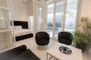 A modern room with a bed, two black chairs, a table with a tray of items, and large windows. - 4 Elemental Living Suites - Wind (Nea Moudania)