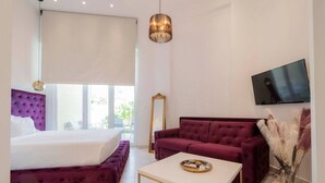 Een moderne hotelkamer met een bed, een bank, een salontafel, een televisie en een groot raam.