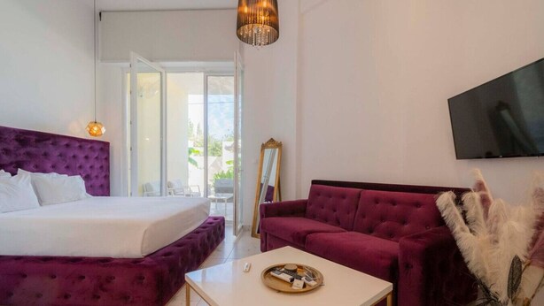 Een slaapkamer met een groot bed, een bank, een televisie en uitzicht op de omgeving.
