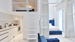 Une chambre moderne avec un lit en mezzanine, un coin cuisine et un espace salon.