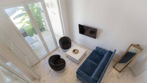 Un salon moderne comprenant un canapé, deux fauteuils, une table basse, un téléviseur à écran plat et un miroir.