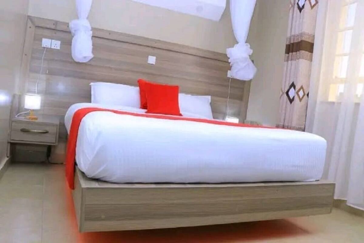 Un lit simple avec une tête de lit en bois, une table de chevet et un oreiller rouge.