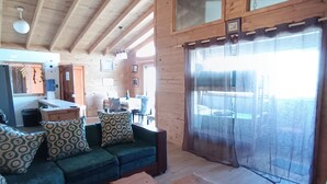A spacious living area with a wooden ceiling, a sofa set, a coffee table, and a large window with curtains. - Haré Tauromi (El Tabo)