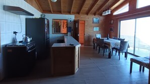 A kitchen with a stove, refrigerator, and dining area with a table and chairs. - Haré Tauromi (El Tabo)
