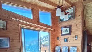 A wooden cabin interior with a dining table, chairs, and a statue centerpiece. - Haré Tauromi (El Tabo)