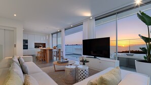 Ett modernt vardagsrum med en soffa, en tv och utsikt över solnedgången.