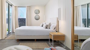 Ett modernt hotellrum med en stor säng, ett sängbord, en spegel och utsikt över omgivningarna.