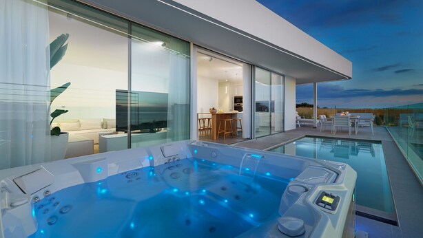 Ett modernt hus med en uppvärmd pool och ett bubbelbad som är inbyggt i glas.