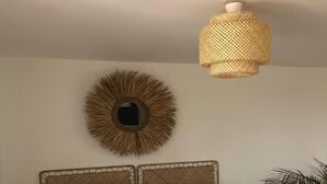 A bed with a grey patterned bedspread, two matching pillows, a woven headboard, a round wall decoration, and a hanging light fixture. - One Bedroom Home In Plouasne (Plouasne)