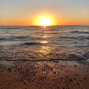 A sunset over a beach with waves and pebbles. - Stay in a beautiful farmhouse on a Apple Orchard (Williamsburg)