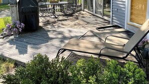 Eine überdachte Terrasse mit Grill, Gartenmöbeln und Blick auf den Garten.