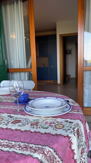 Een eettafel met een tafelkleed met bloemen, een wijnglas en blauwe en witte borden.