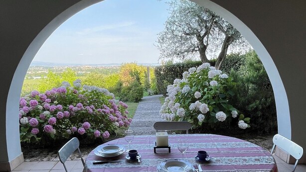 Un área de comedor al aire libre con una mesa preparada para cuatro personas, con vistas a un jardín.
