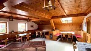 Een rustiek houten interieur met een loft-plafond, houten banken, tafels en een grote houten kist.