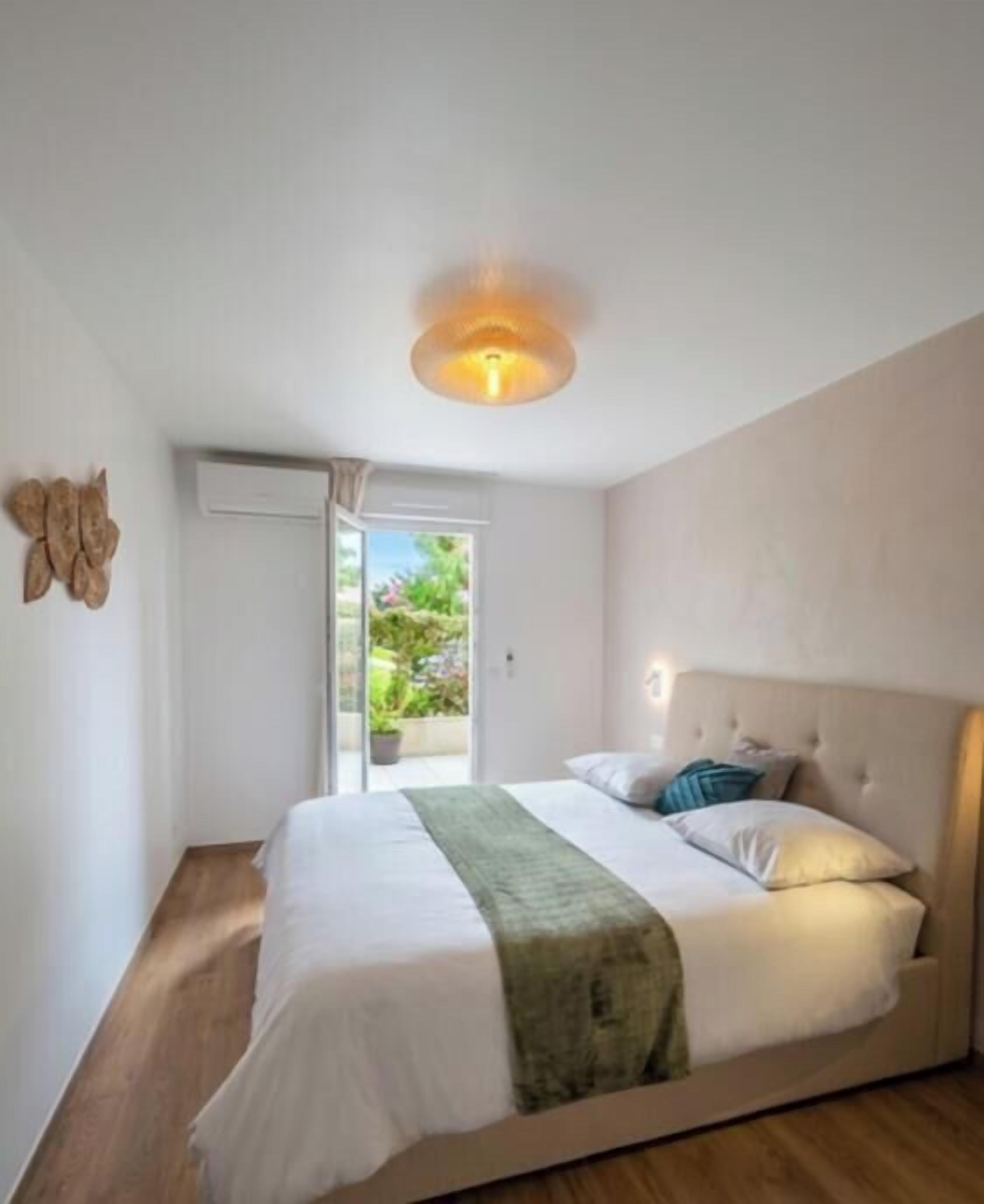 Une chambre à coucher comprenant un lit, une lampe de chevet, une fenêtre et une porte donnant sur un espace extérieur.