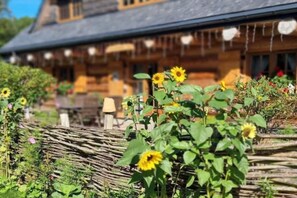 A wooden house with a thatched roof and a garden with sunflowers. - Comfortable apartment, 2 levels, close to beach (Ustronie Morskie)